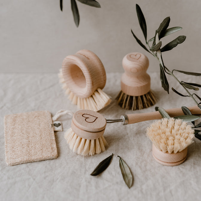 Verschiedene Spülbürsten aus Holz und Luffa Schwamm auf einem Tisch liegend