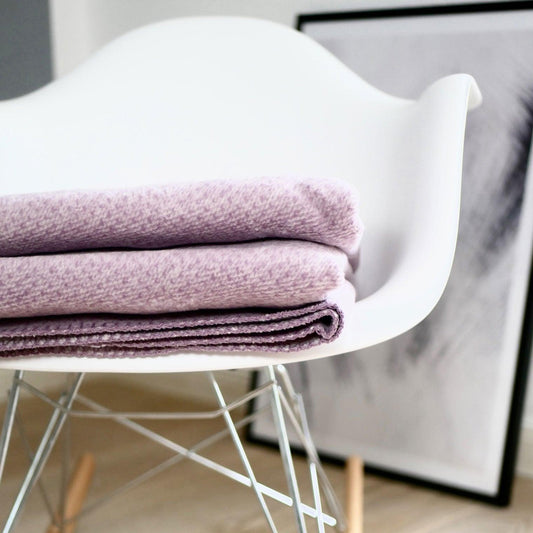 Malvefarbene Baumwolldecke auf einem weißen Stuhl liegend
