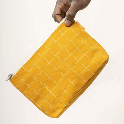 Gelbe Kosmetiktasche aus Baumwolle mit Reißverschluss in Hand gehalten