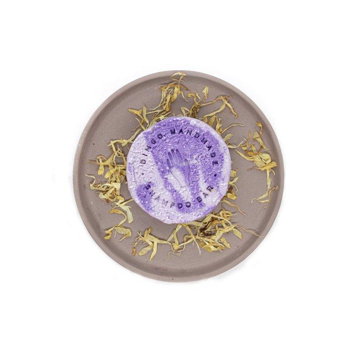 Runde und lilafarbenes festes Haarshampoo auf einem Teller liegend neben Lavendelblüten